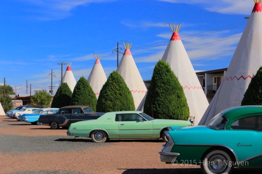 "Tepees" at Wigwam motel. Antique cars are parked outside most of the units.